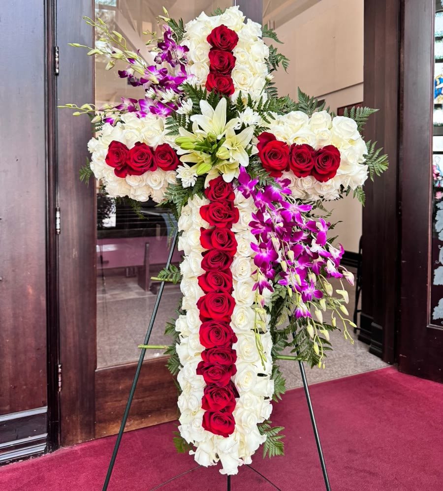 Flower cross of white and red roses with lilies and purple orchids.